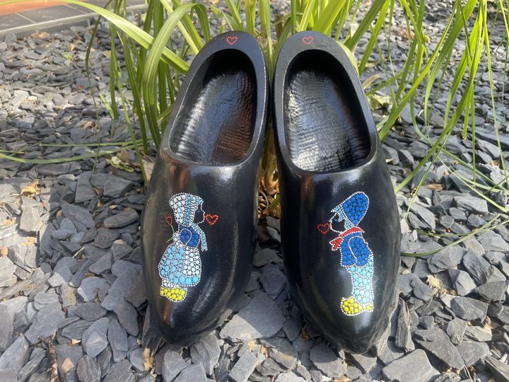 Twee zwarte klompen met een gestipt kussend Hollands paartje in blauw